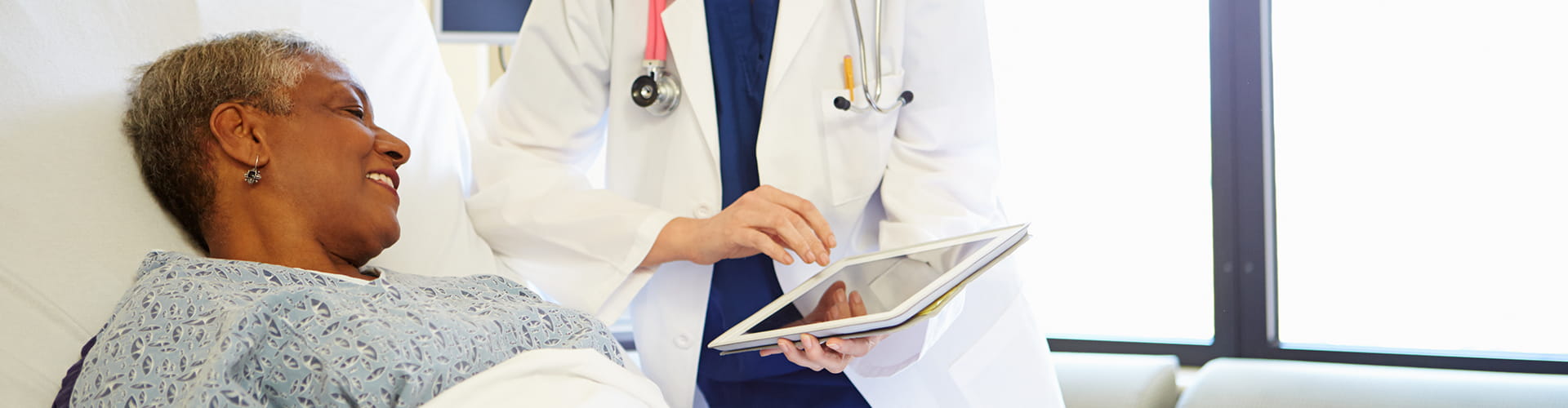 Doctor showing tablet to a patient in a hospital bed