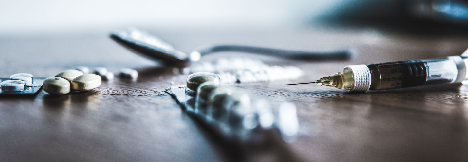 Hypodermic needles and pills on a table