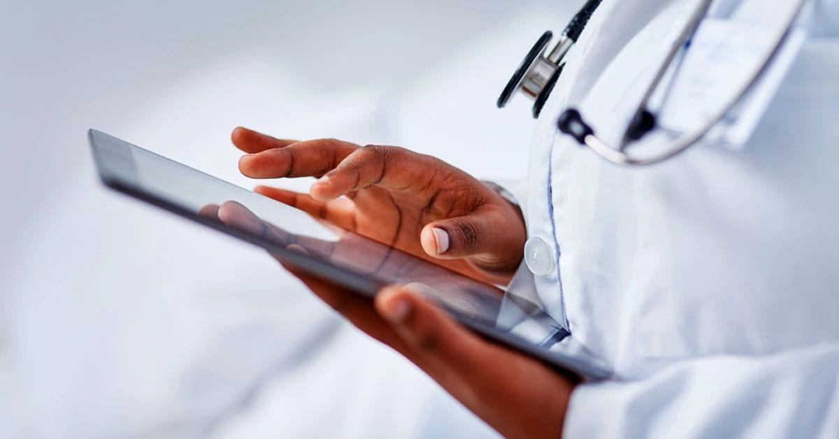 A close-up of a doctor typing on a tablet
